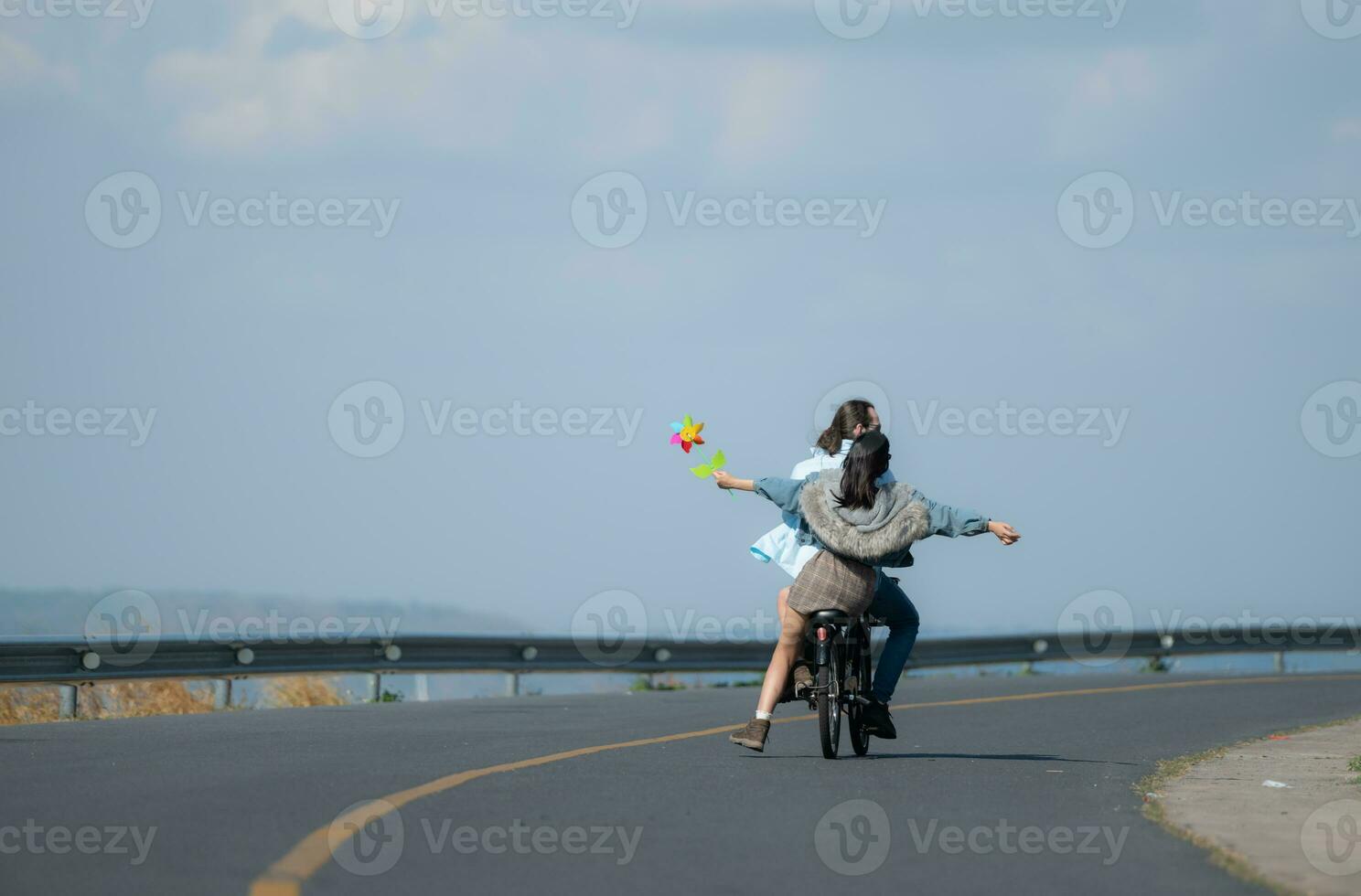 espalda ver de un joven mujer montando un bicicleta con su novio en el la carretera foto