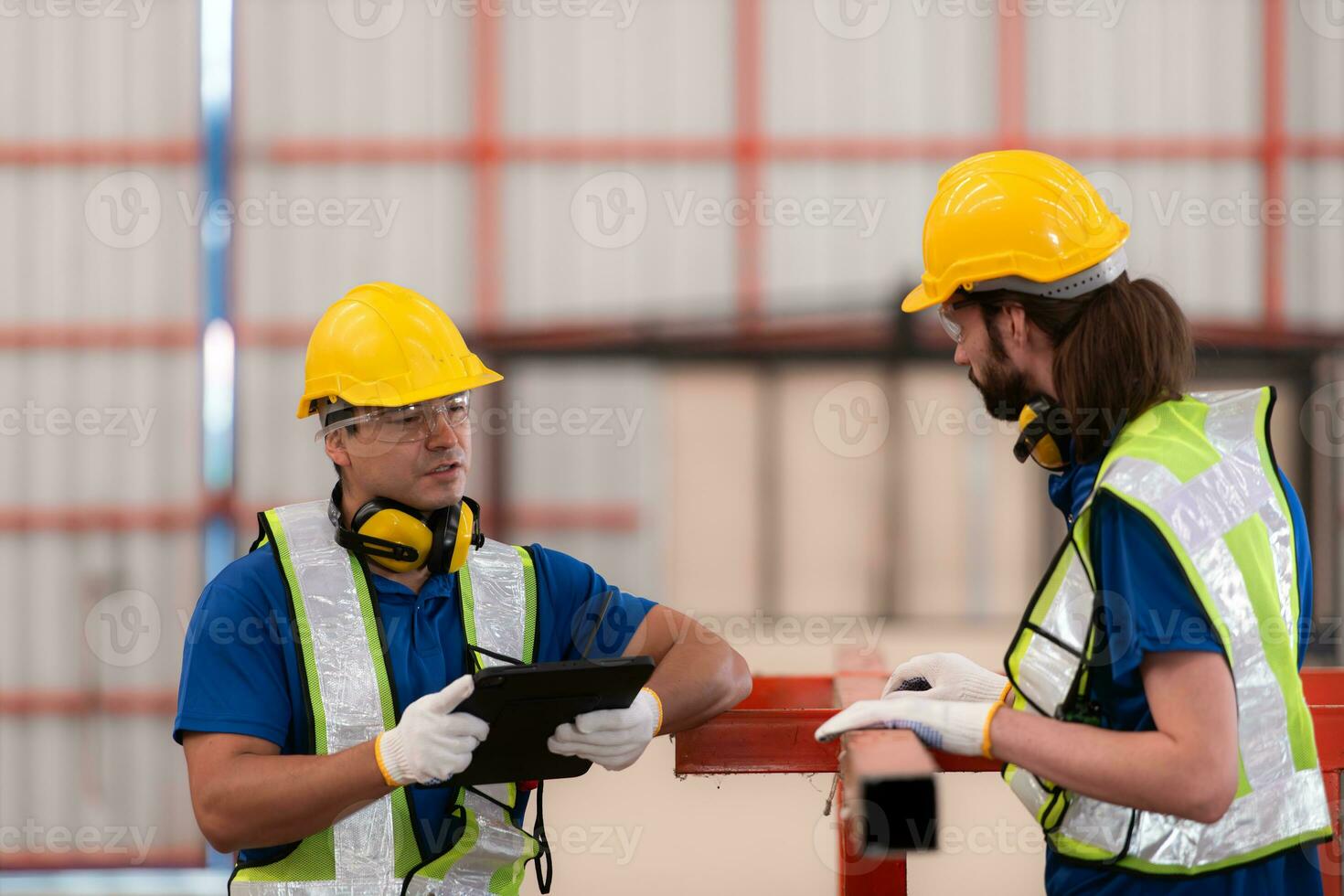 Portrait of two workers using digital tablet stand in front of the red steel structure photo