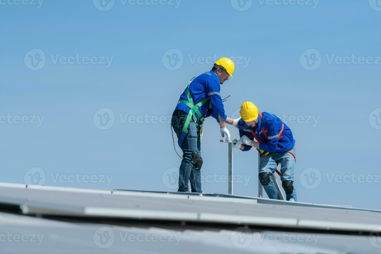 A young technician intern working on solar panels is fear of heights with senior engineers who are always helping out photo