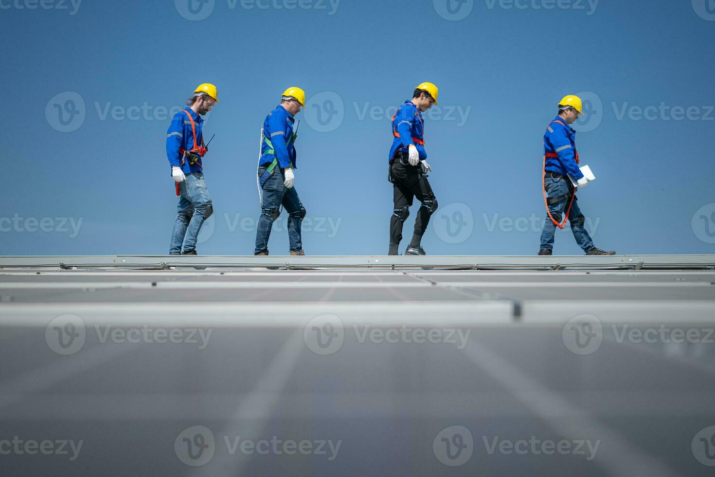 Group of engineers standing on solar panels with blue sky in the background photo