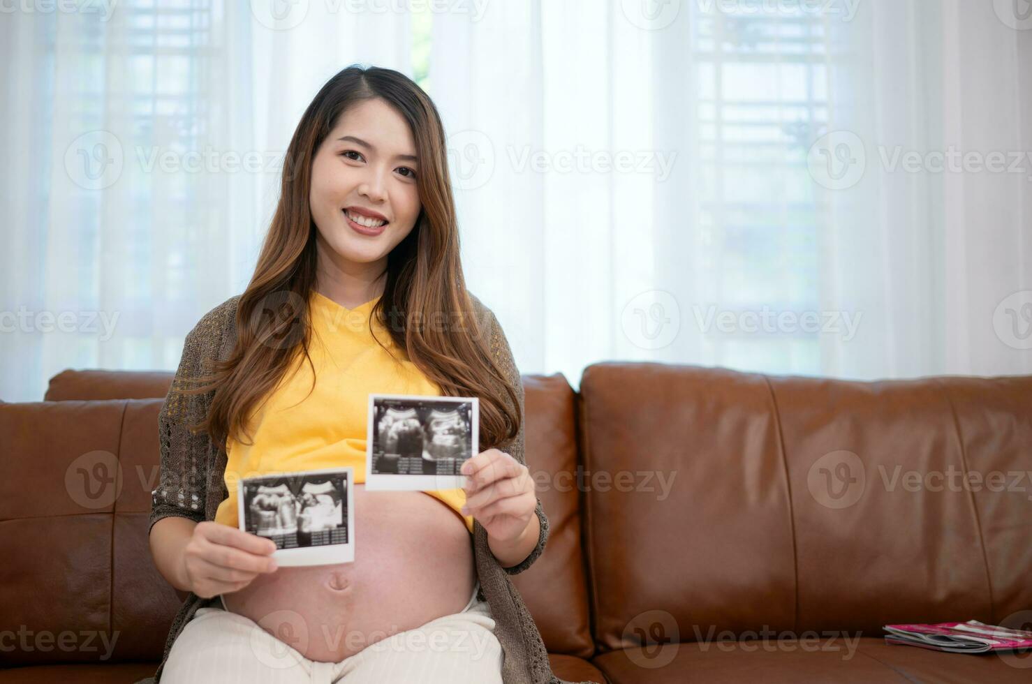 Pregnant asian woman holding ultrasound picture of her baby. photo