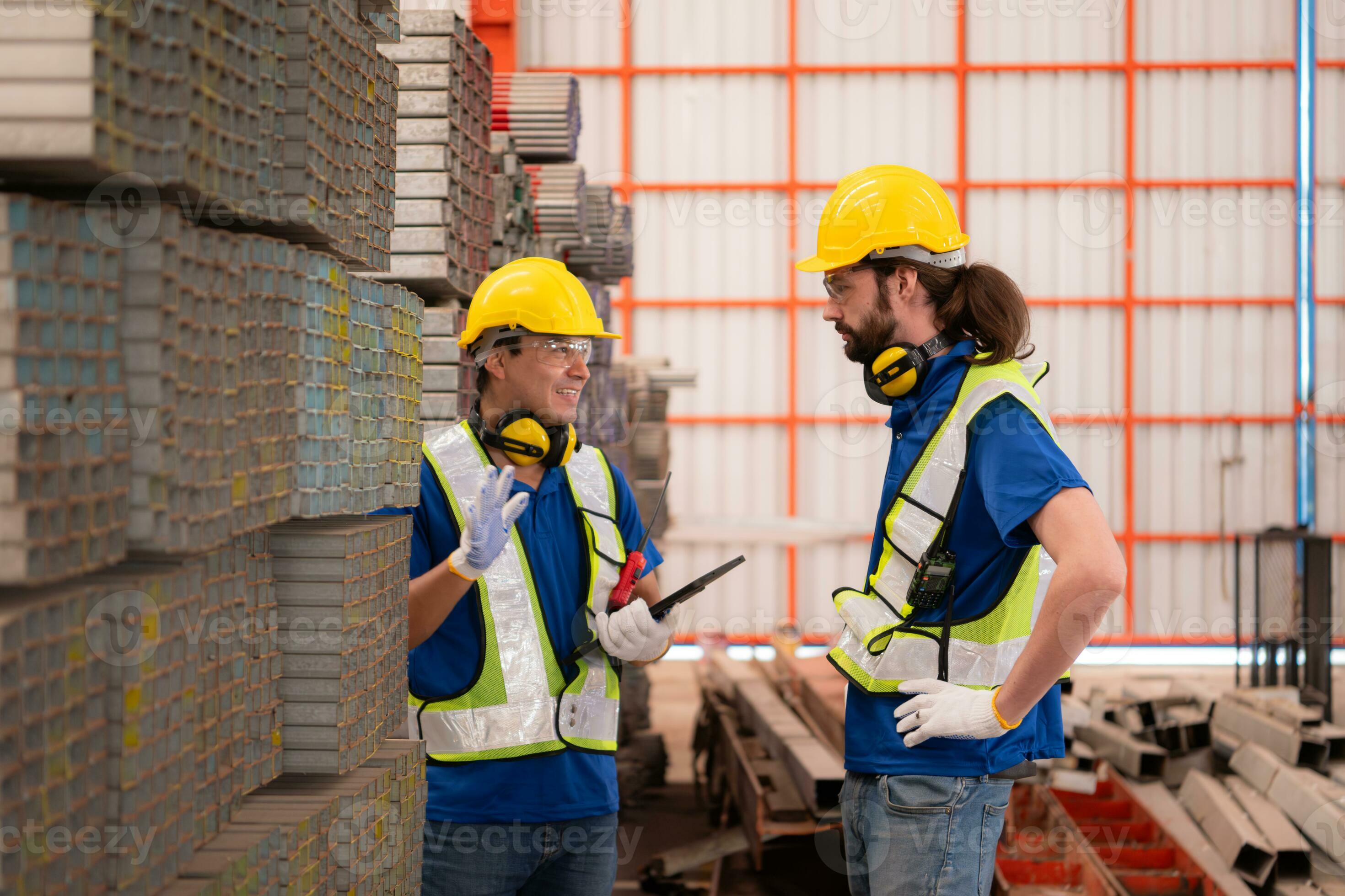 Warehouse workers in hard hats and helmets stand in the warehouse to