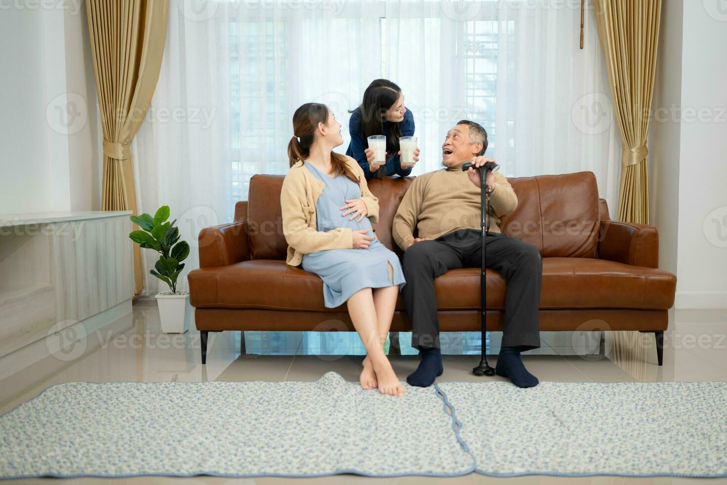 A happy family sits on the sofa in the living room, Father and daughter are pregnant drinking milk and talk to each other. photo