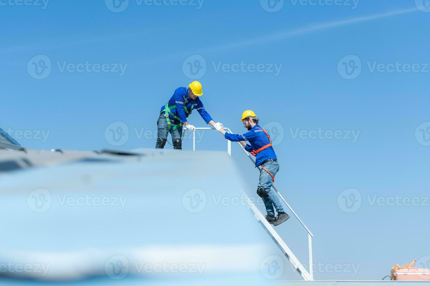 A young technician intern working on solar panels is fear of heights with senior engineers who are always helping out photo