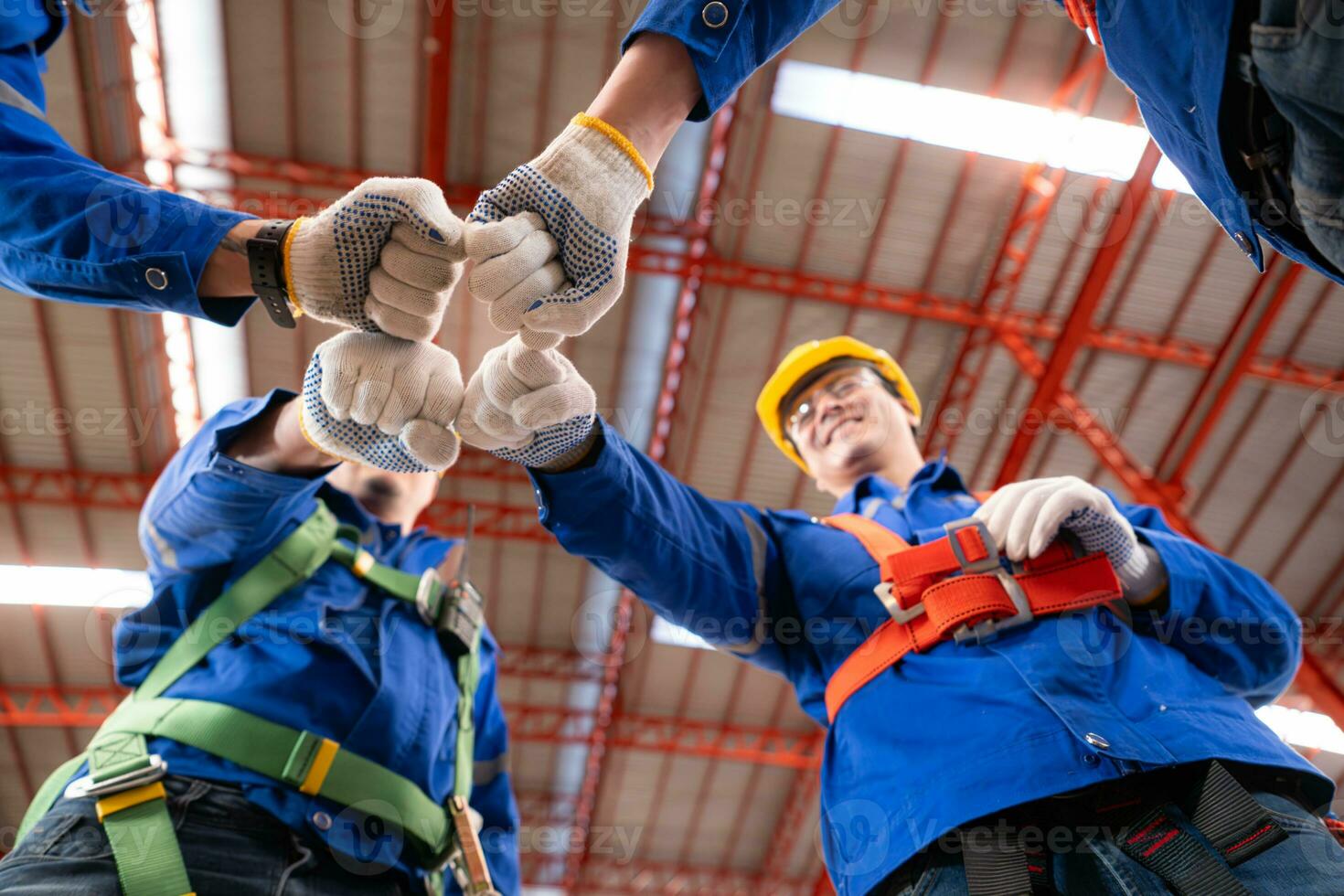 Under view of a team of industrial workers standing together in a warehouse, Focus on fist bump hands together photo