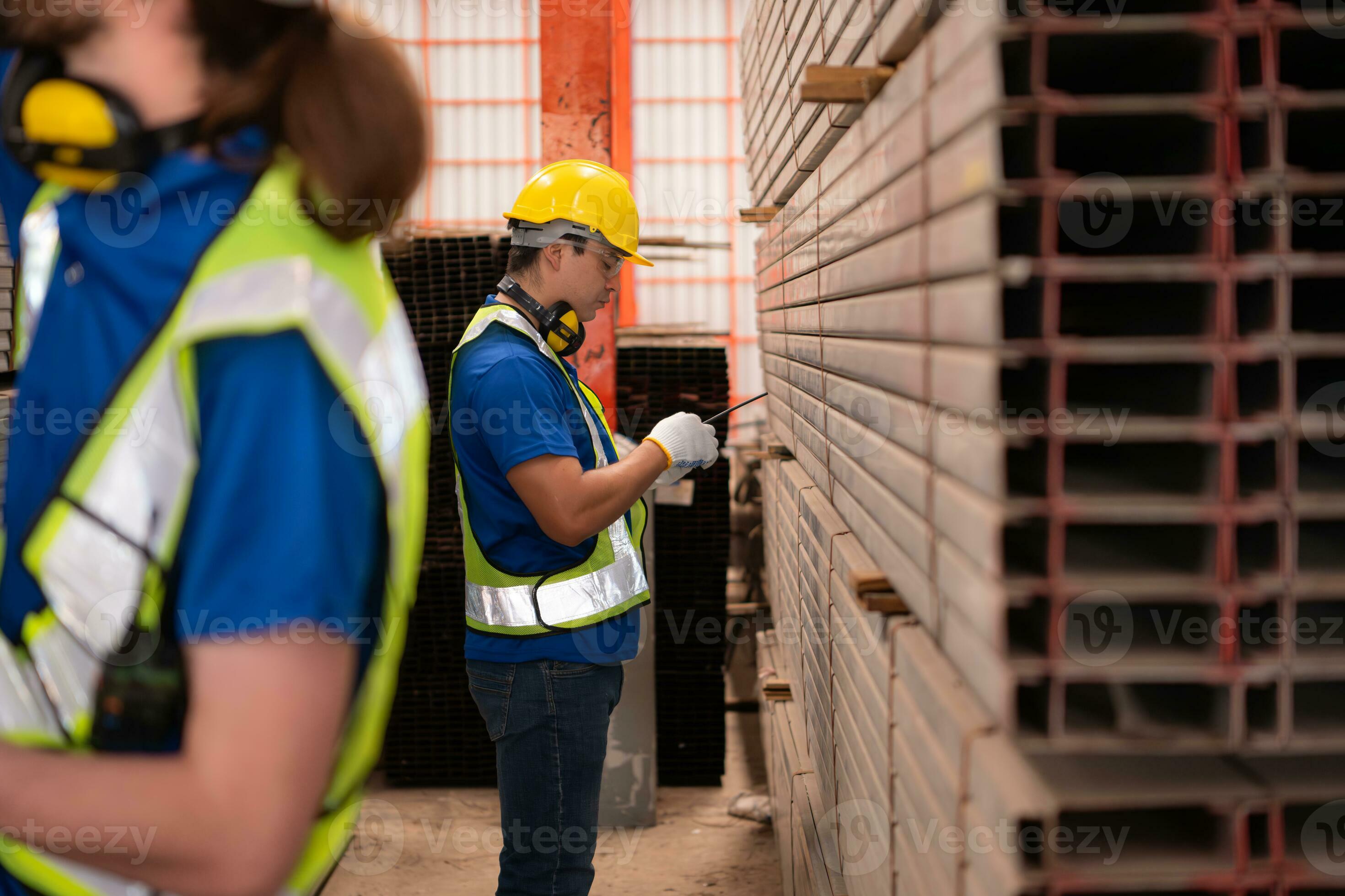 Warehouse workers in hard hats and helmets stand in the warehouse to