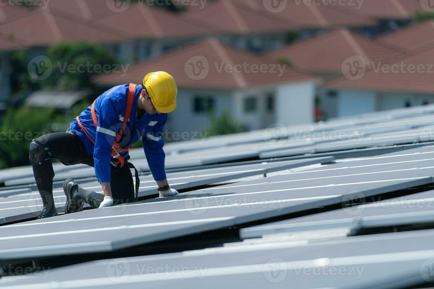 A technician is installing solar panels on the roof of the warehouse to change solar energy into electrical energy for use in factories. photo