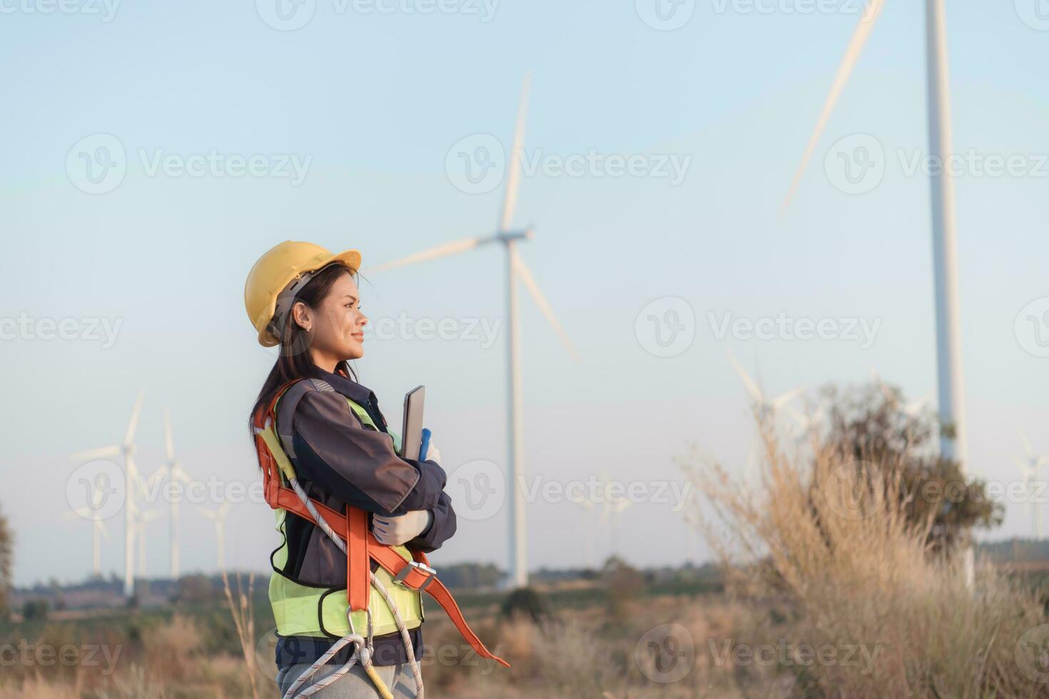 hembra ingeniero vistiendo la seguridad casco y participación ordenador portátil en viento turbina granja. foto