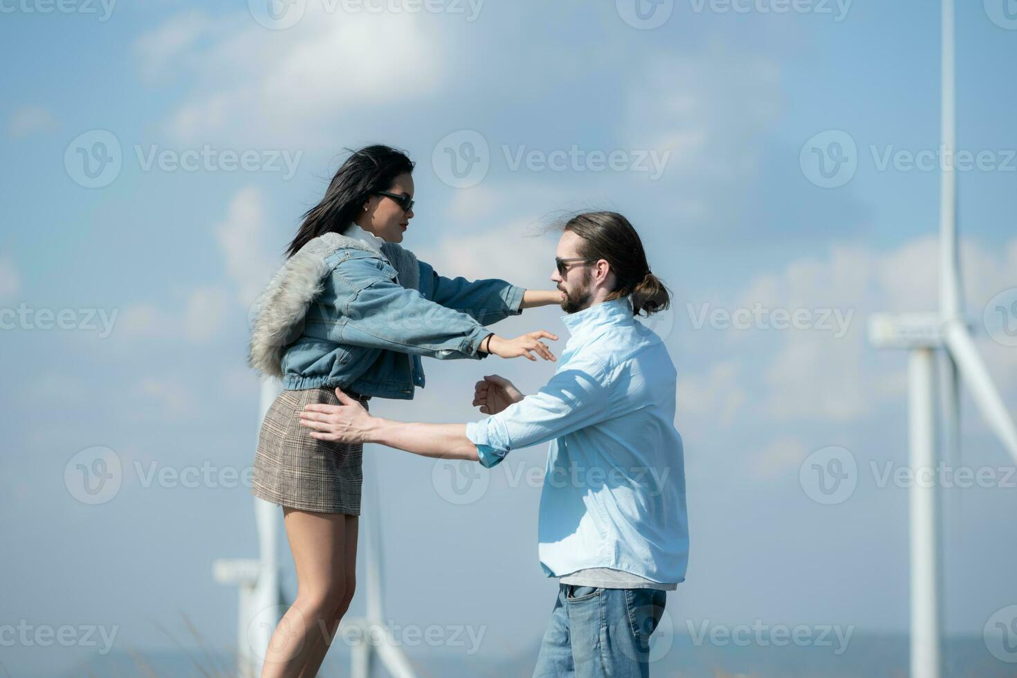 Back view of young couple walking on the road with wind turbines in background photo