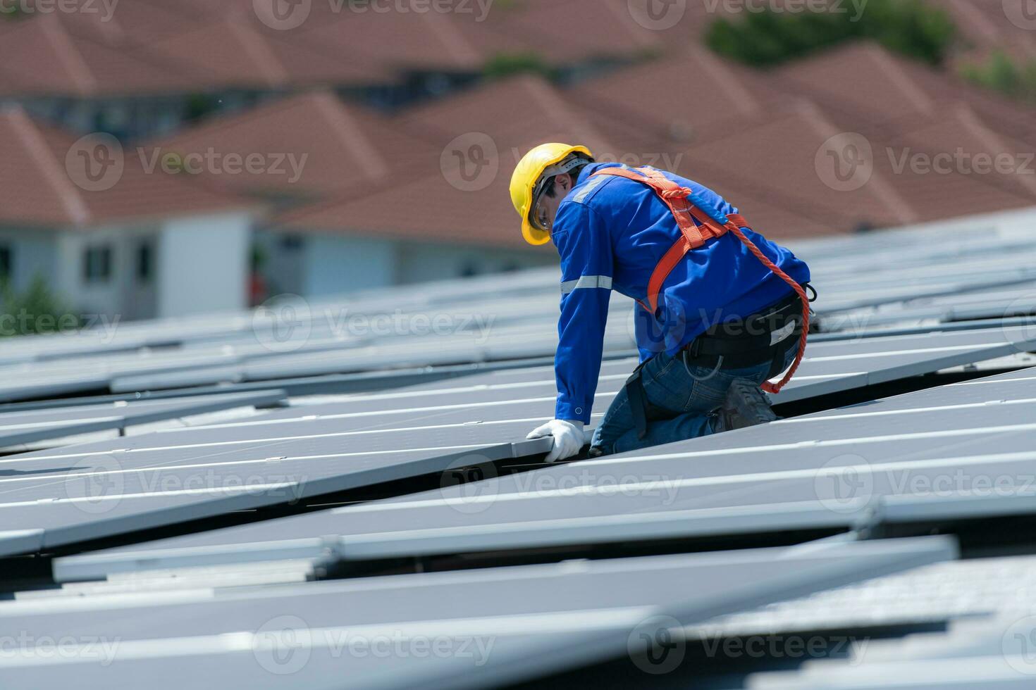 A technician is installing solar panels on the roof of the warehouse to change solar energy into electrical energy for use in factories. photo