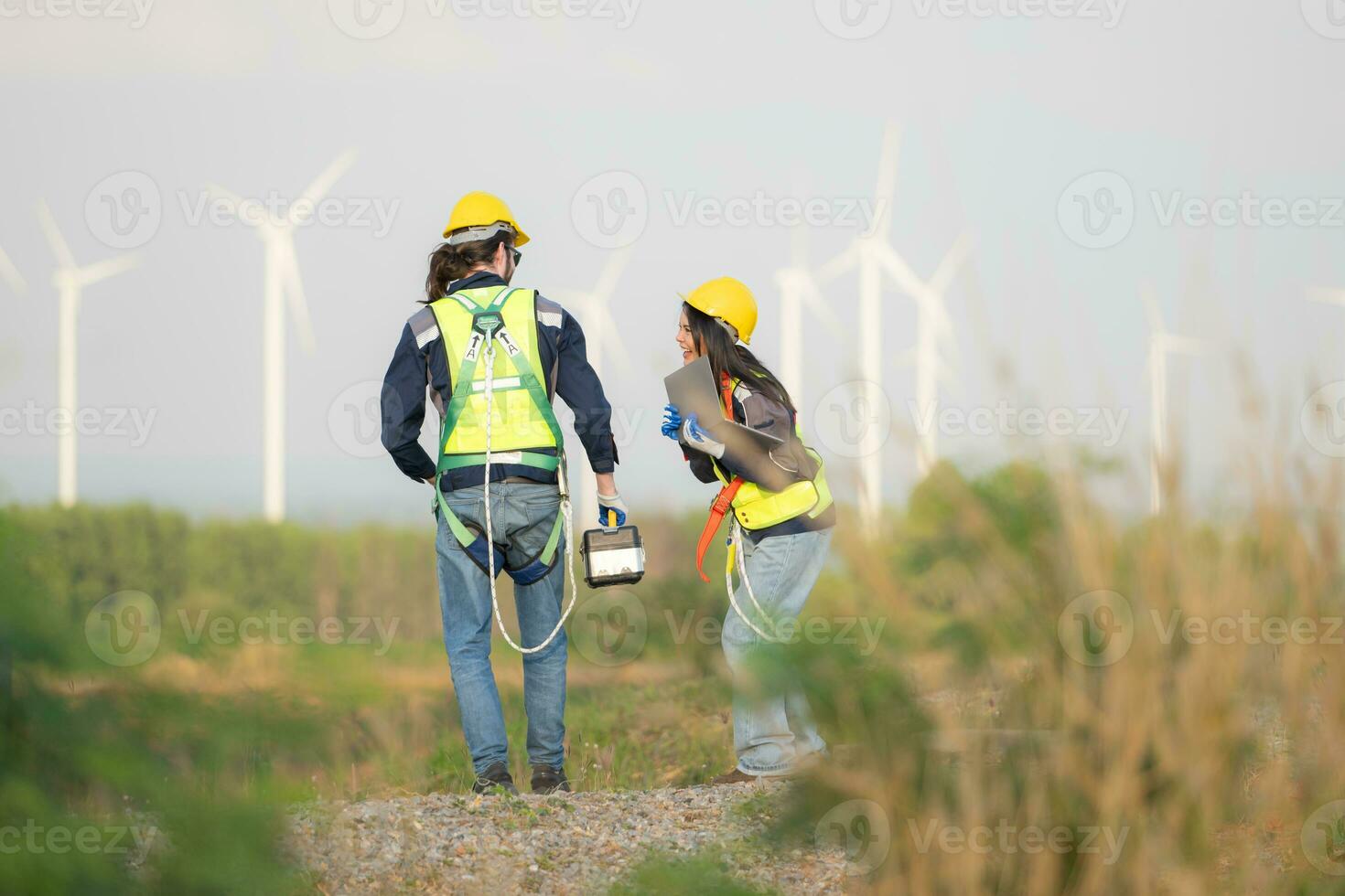Engineer and worker discussing on a wind turbine farm with laptop photo