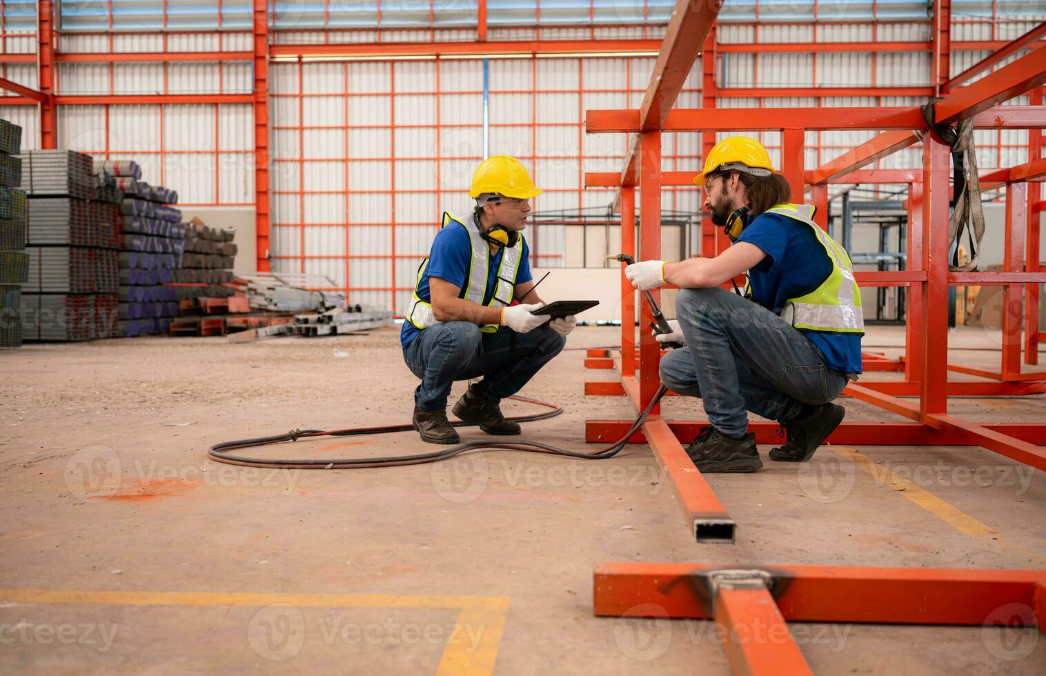 Portrait of two workers using digital tablet sit in front of the red steel structure photo