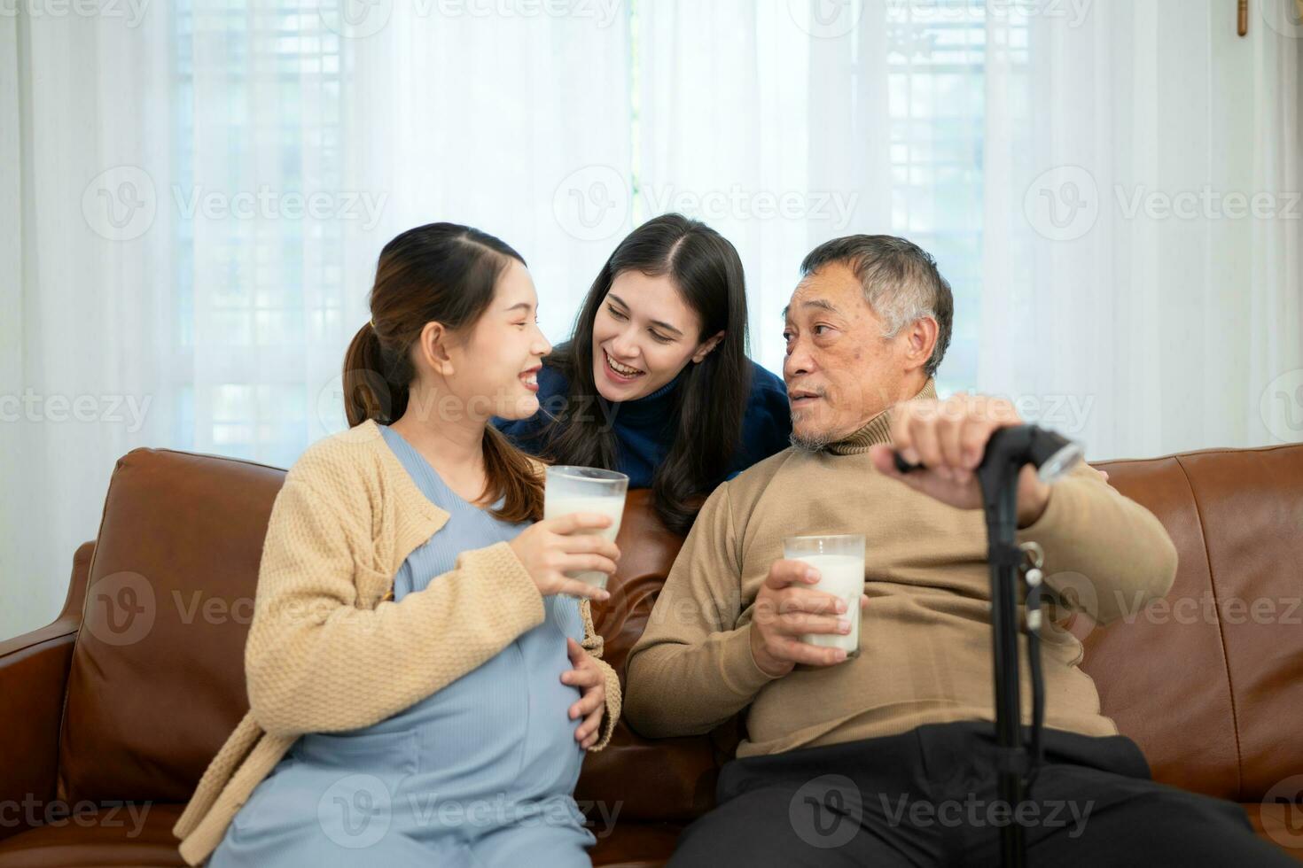 A happy family sits on the sofa in the living room, Father and daughter are pregnant drinking milk and talk to each other. photo