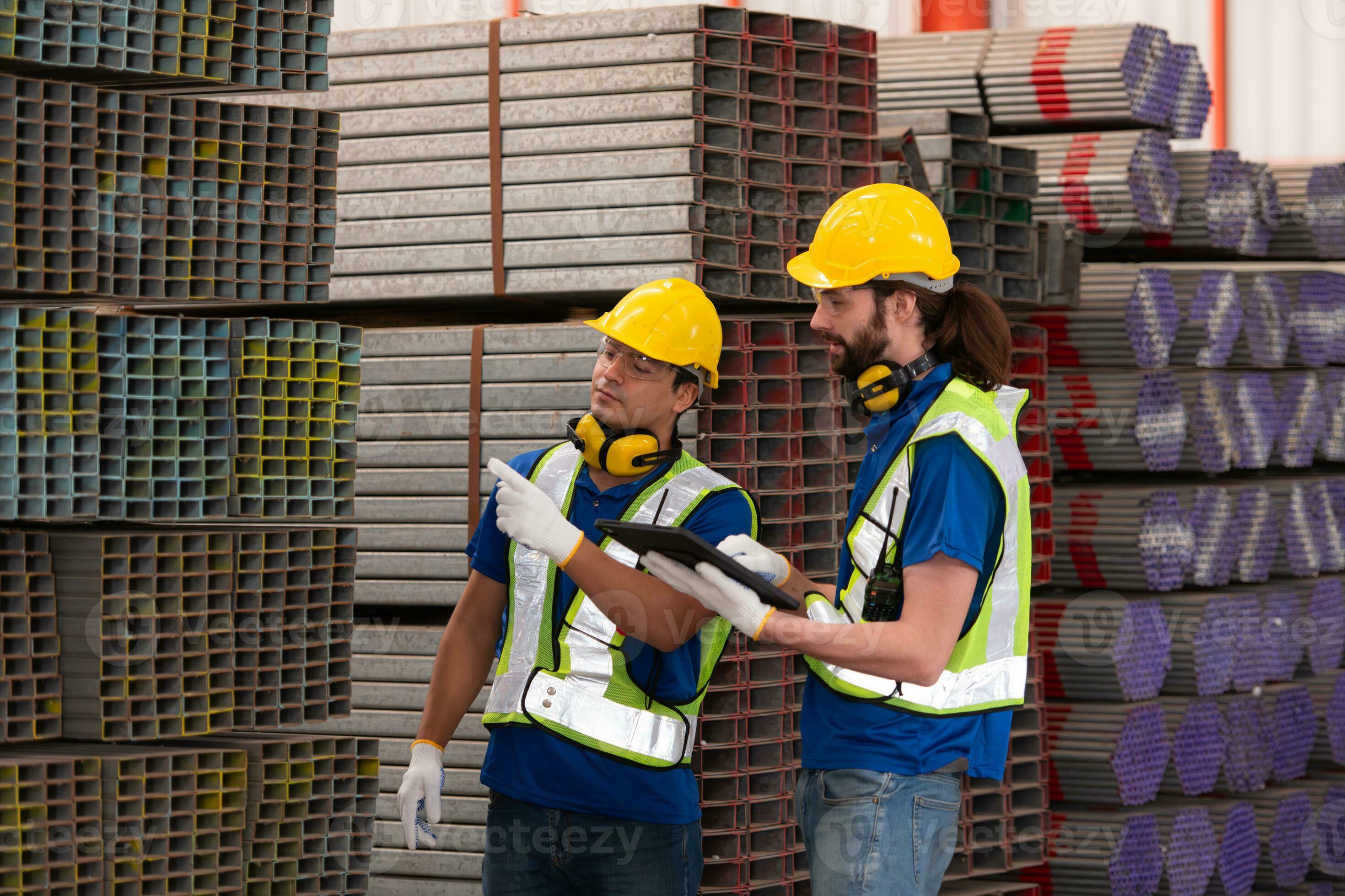 Warehouse workers in hard hats and helmets stand in the warehouse to