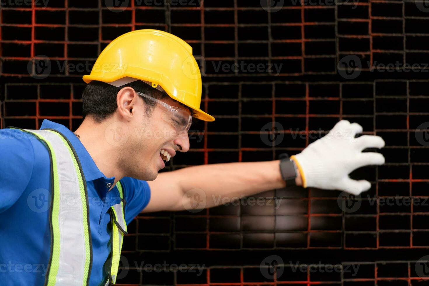 retrato de un masculino trabajador vistiendo un la seguridad chaleco y casco sentado en un aceros paleta debido a espalda dolor desde trabajando en un fábrica levantamiento pesado cosas. foto