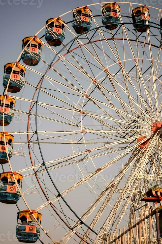 Closeup of multi-coloured Giant Wheel during Dussehra Mela in Delhi, India. Bottom view of Giant Wheel swing. Ferriswheel with colourful cabins during day time. photo