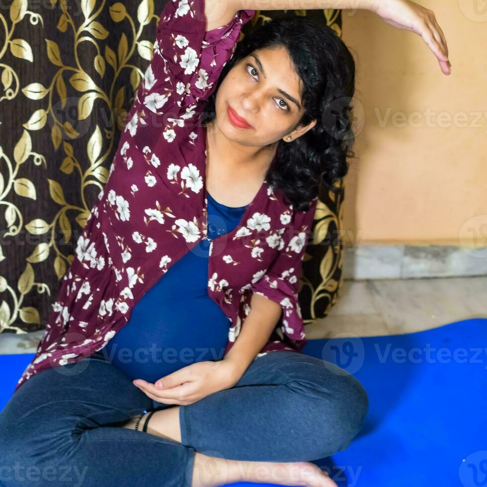Pregnant woman doing Pregnancy yoga pose comfortable at home with belly, Pregnant woman practicing simple yoga steps at home, Pregnancy yoga and fitness poses photo