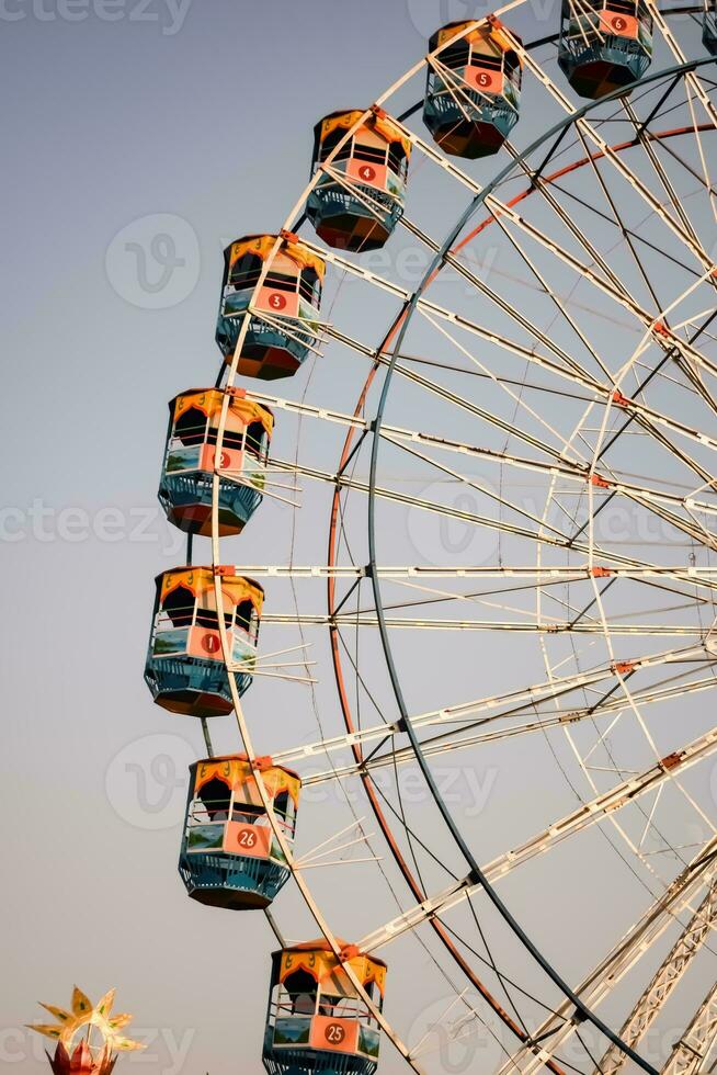 Closeup of multi-coloured Giant Wheel during Dussehra Mela in Delhi, India. Bottom view of Giant Wheel swing. Ferriswheel with colourful cabins during day time. photo