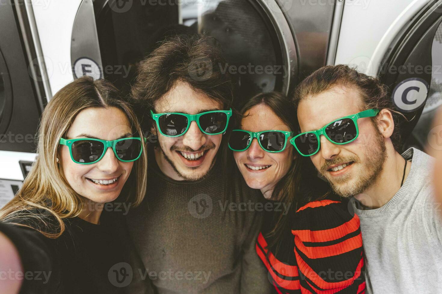 grupo de joven amigos vistiendo verde Gafas de sol teniendo divertido tomando un selfie foto