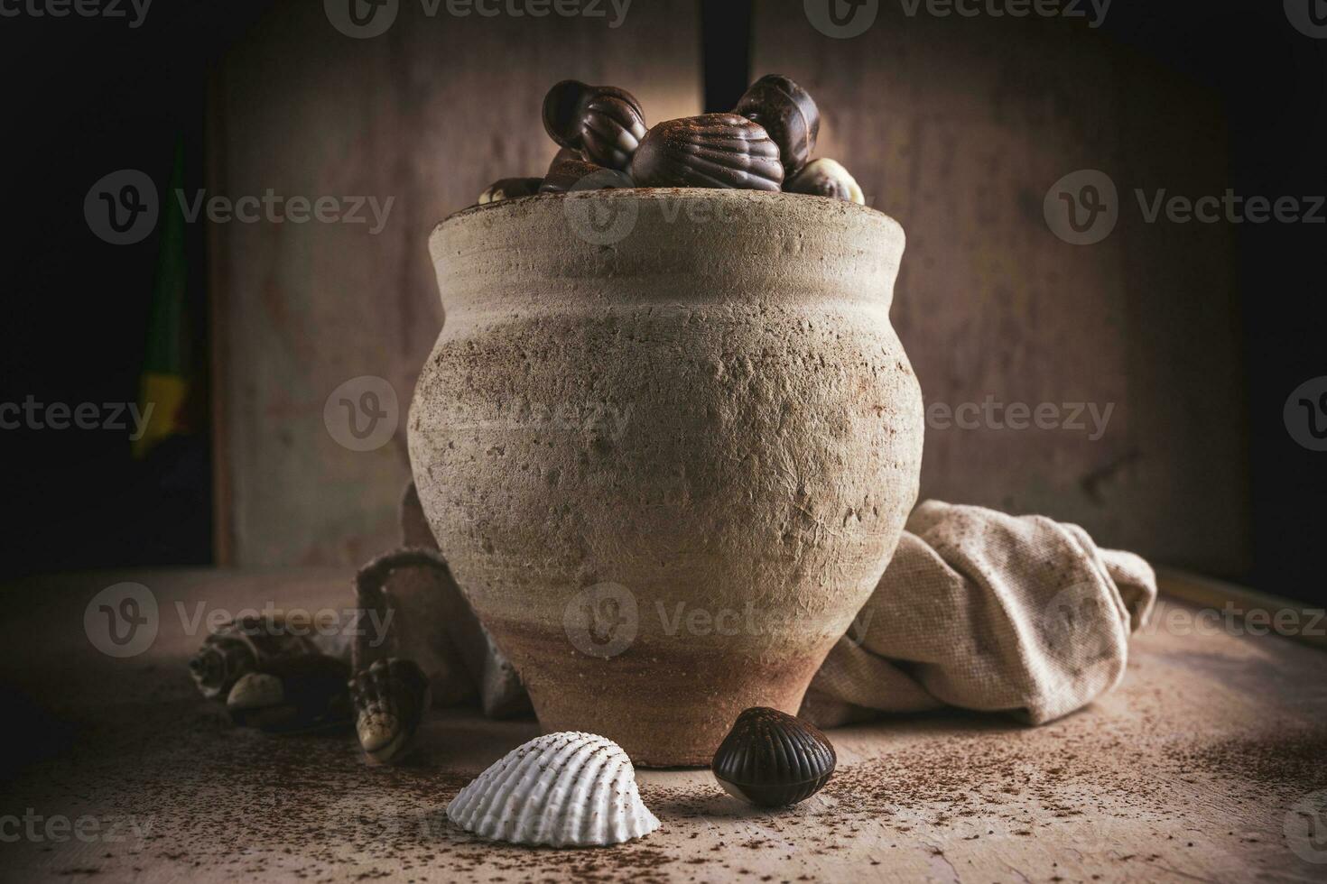 shell shaped chocolates with cream in a clay jar photo