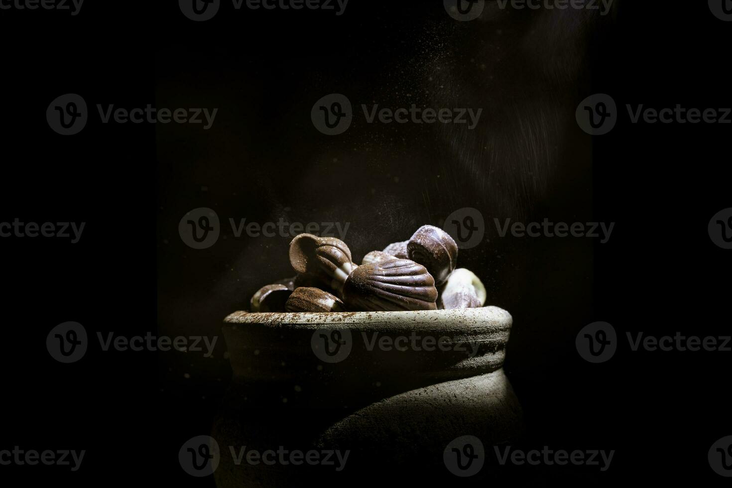 shell shaped chocolates with cream in a clay jar photo