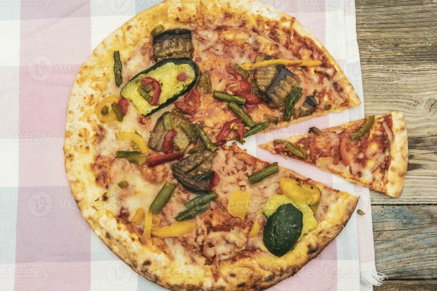 Tasty grilled vegetable pizza cooked with ingredients on wooden background photo