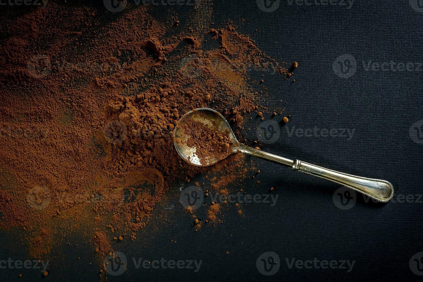 bitter cocoa powder and a silver spoon on a black background photo