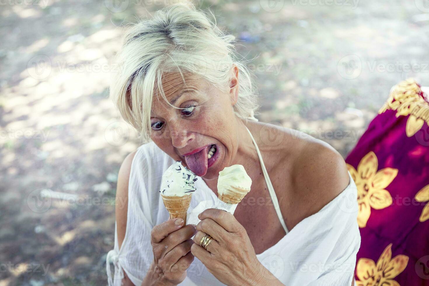hermosa dama comiendo hielo crema sentado en un silla de cubierta foto