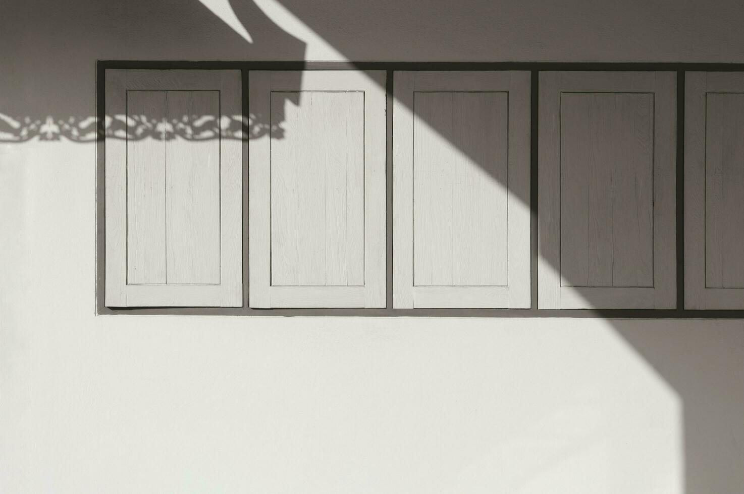 Sunlight and shadow on surface of wooden windows on cement wall of vintage house in sepia tone style photo