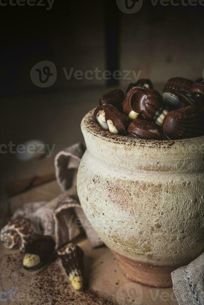 shell shaped chocolates with cream in a clay jar photo