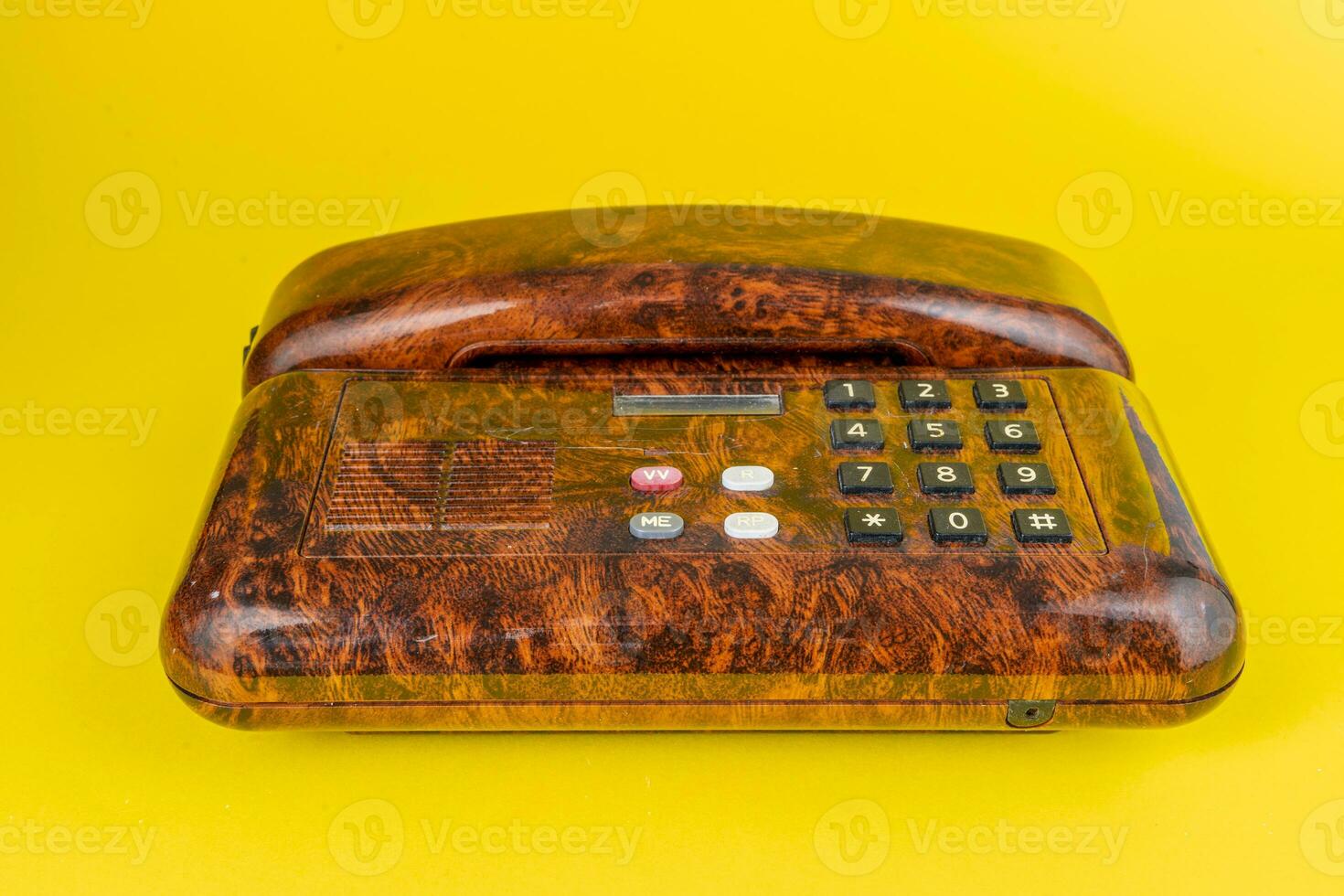 vintage telephone in imitation briar wood over a yellow background photo