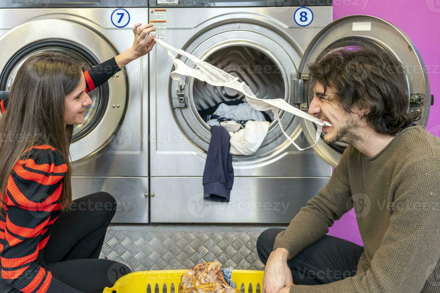 young couple is putting clothes in the washing machine drum photo
