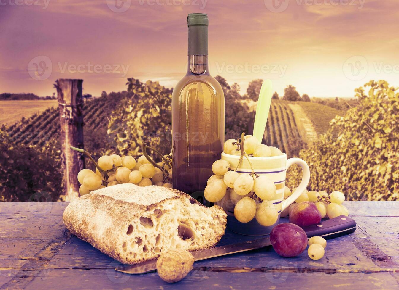 bread grapes and a bottle of wine over wooden boards photo