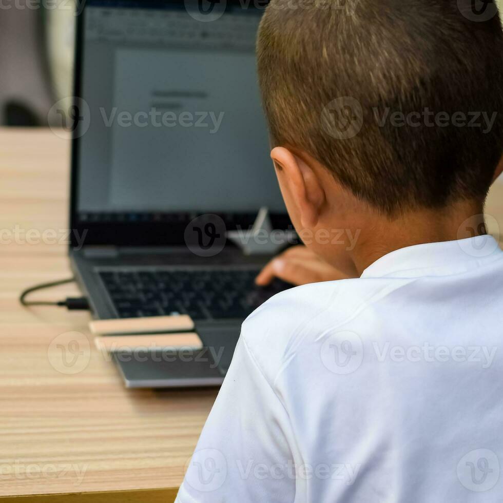 Little boy sitting at table using laptop for online class in Grade 1, Child studying on laptop from home for distance learning online education, School boy children lifestyle concept photo