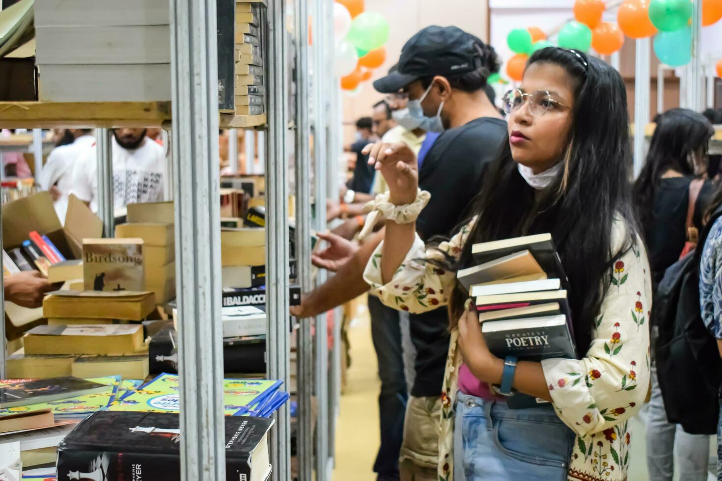 Delhi, India, September 09 2023 - Various age group people reading variety of Books on shelf inside a book-stall at Delhi International Book Fair, Selection of books on display in Annual Book Fair photo