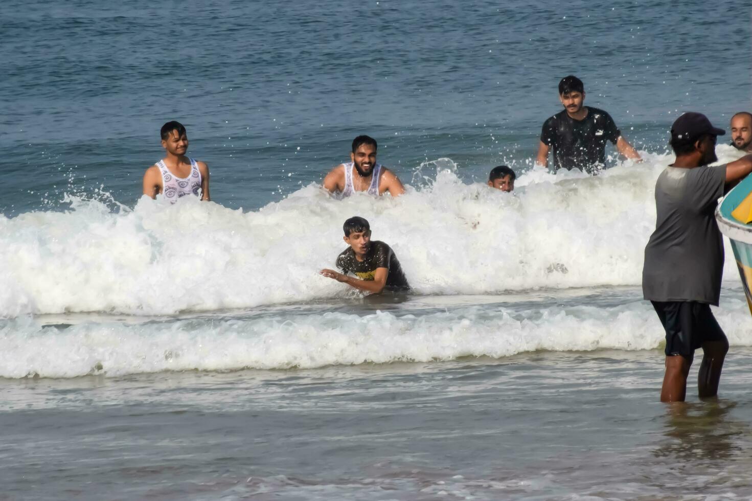 Goa, India, December 10, 2023 - Unidentified tourists enjoying at Arabian sea during the morning time in Calangute beach Goa, India, Ocean beach view early morning time photo