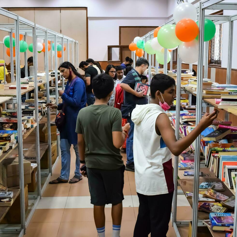 Delhi, India, September 09 2023 - Various age group people reading variety of Books on shelf inside a book-stall at Delhi International Book Fair, Selection of books on display in Annual Book Fair photo