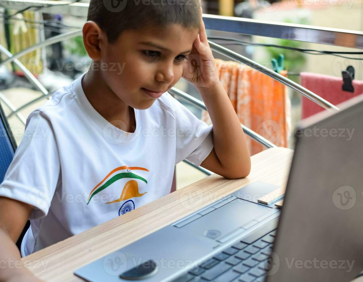 Little boy sitting at table using laptop for online class in Grade 1, Child studying on laptop from home for distance learning online education, School boy children lifestyle concept photo