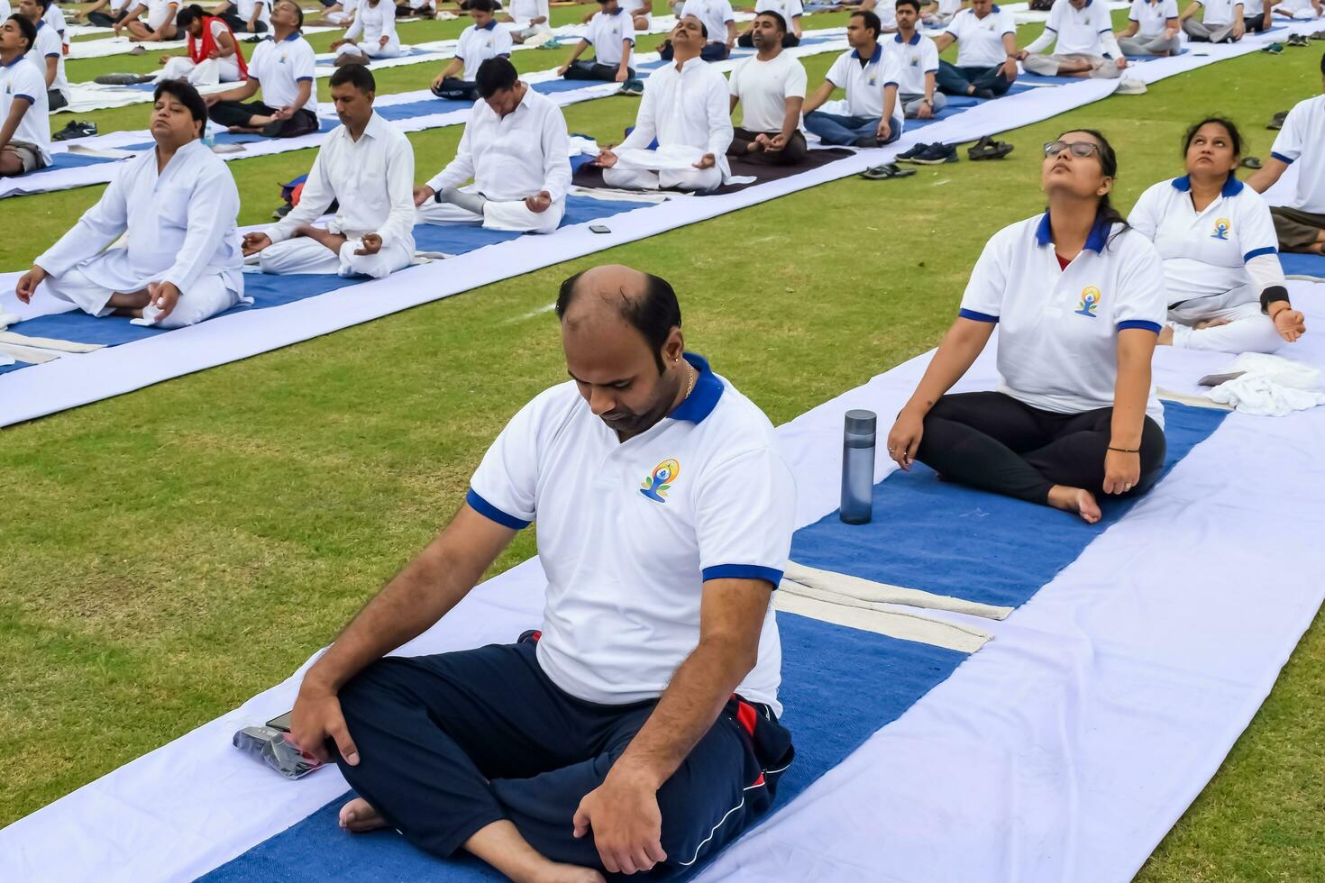 New Delhi, India, June 21, 2023 - Group Yoga exercise session for people at Yamuna Sports Complex in Delhi on International Yoga Day, Big group of adults attending yoga class in cricket stadium photo