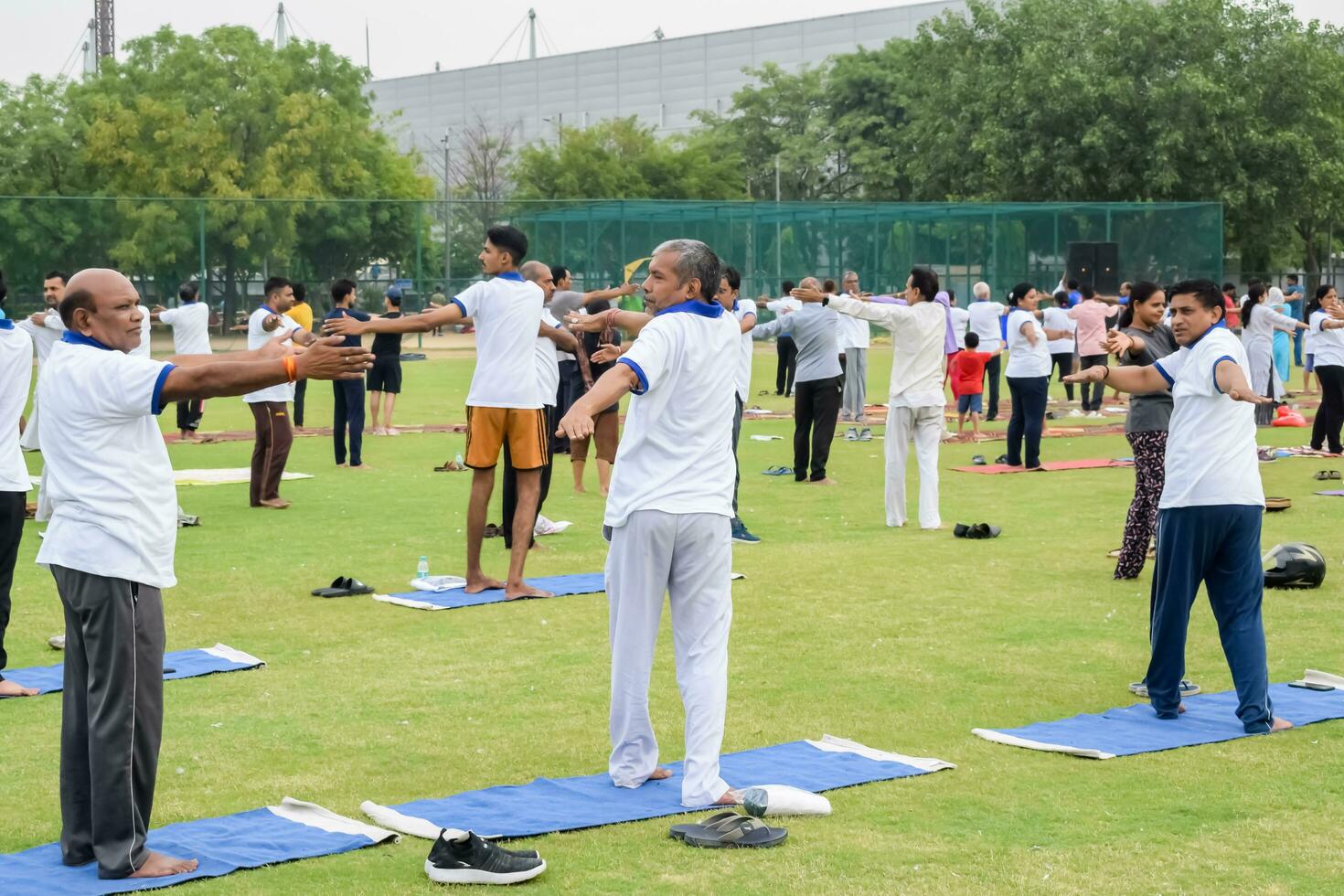 New Delhi, India, June 21, 2023 - Group Yoga exercise session for people at Yamuna Sports Complex in Delhi on International Yoga Day, Big group of adults attending yoga class in cricket stadium photo