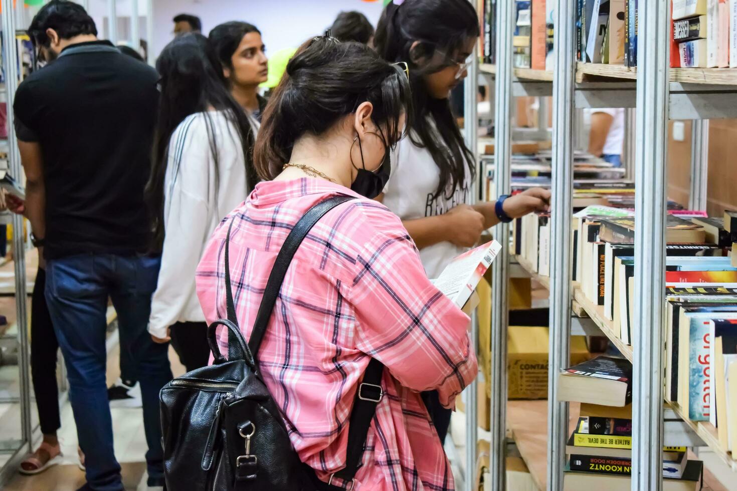 Delhi, India, September 09 2023 - Various age group people reading variety of Books on shelf inside a book-stall at Delhi International Book Fair, Selection of books on display in Annual Book Fair photo