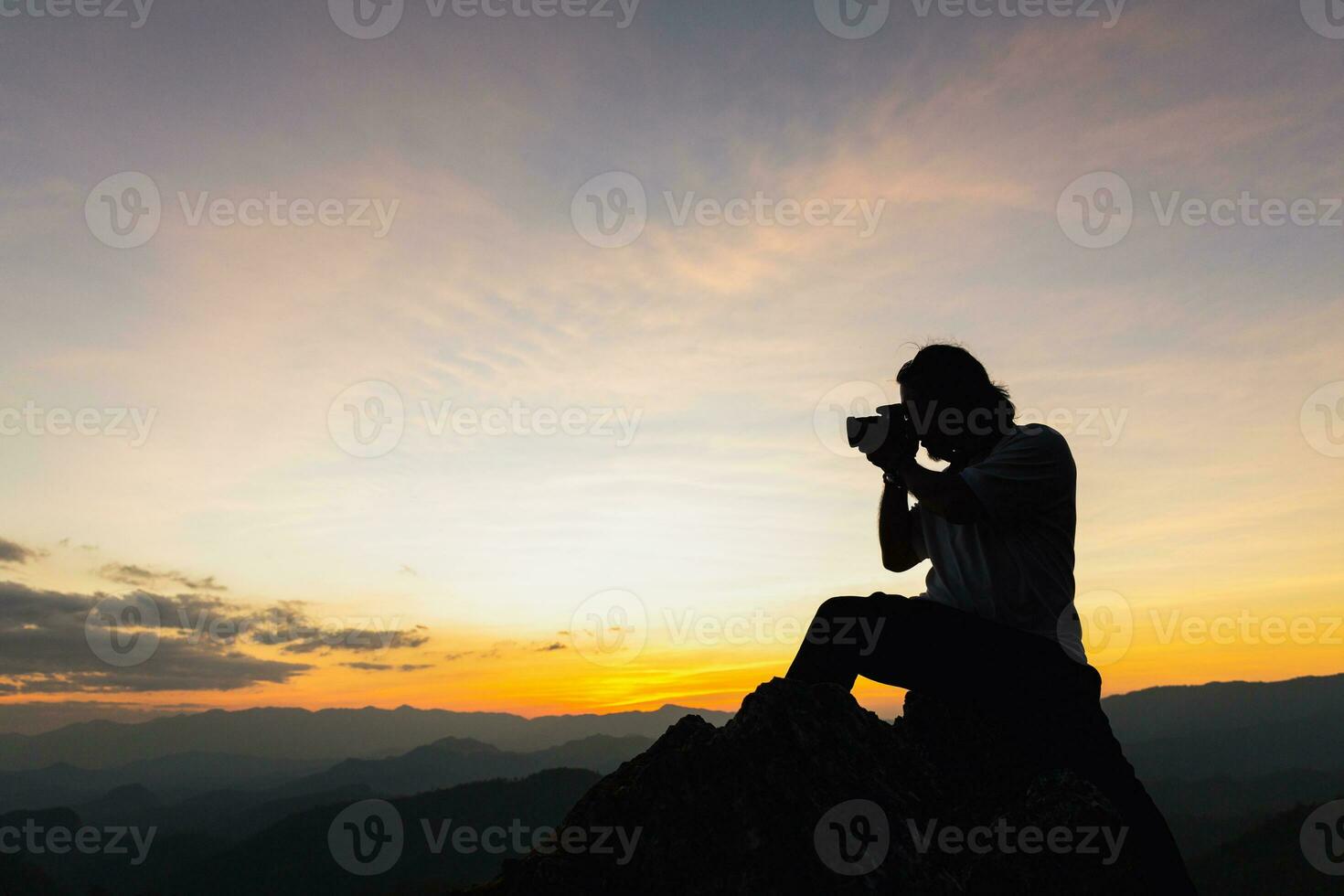 Silhouette of a photographer on top of a mountain at sunset photo