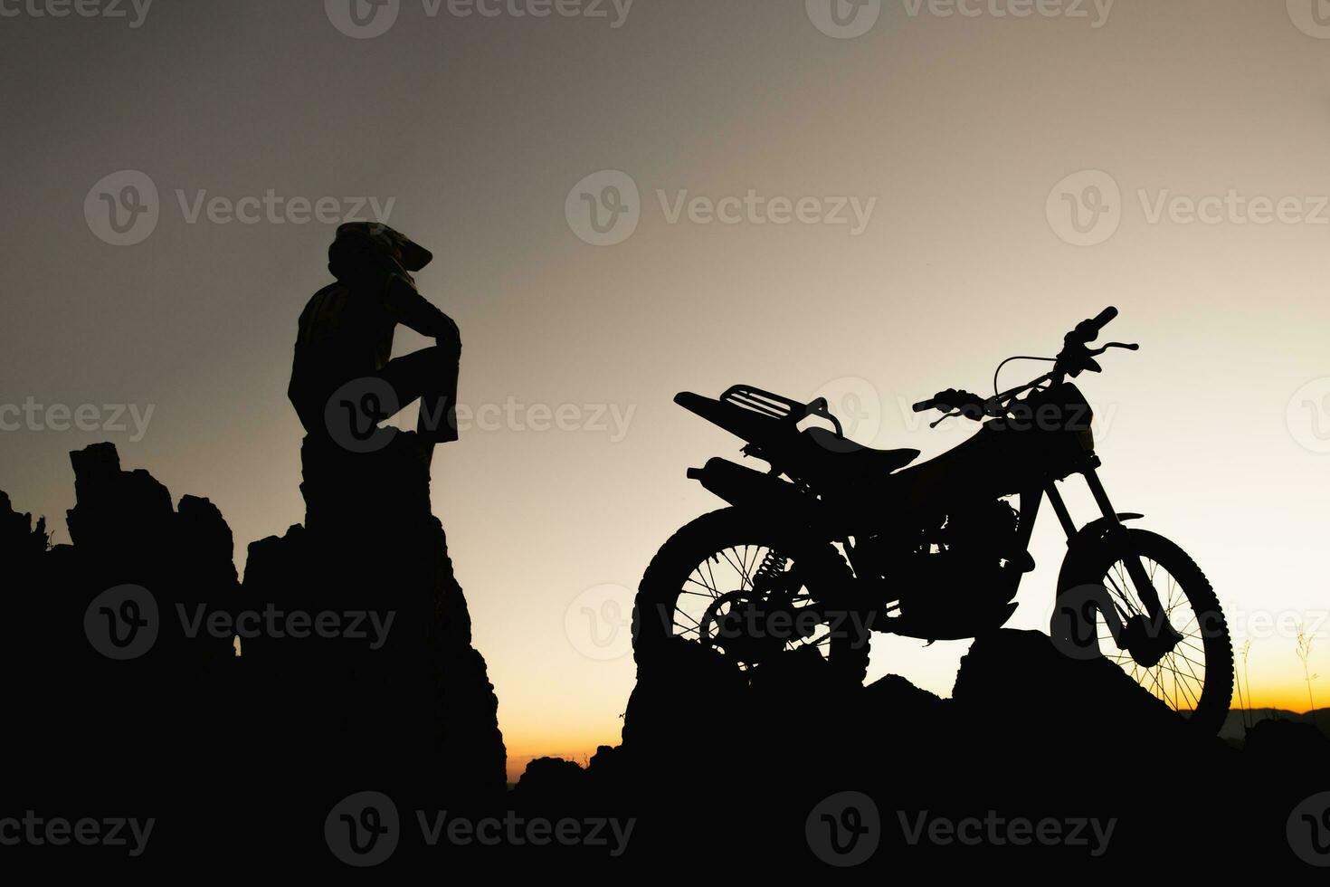 hombre con motocross bicicleta en contra hermosa luces, silueta de un hombre con motocross motocicleta en parte superior de rock alto montaña a hermosa atardecer, enduro motocicleta viaje concepto. foto