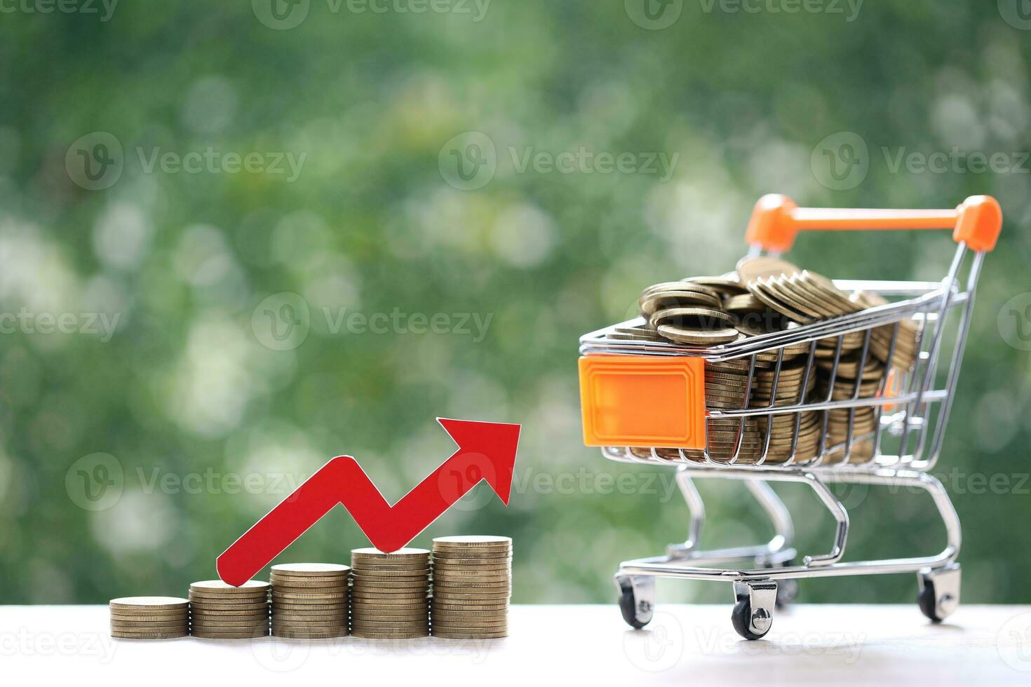 Global inflation or Deflation concept, Red arrow graph on stack of coins money and model miniature shopping cart on natural green background photo