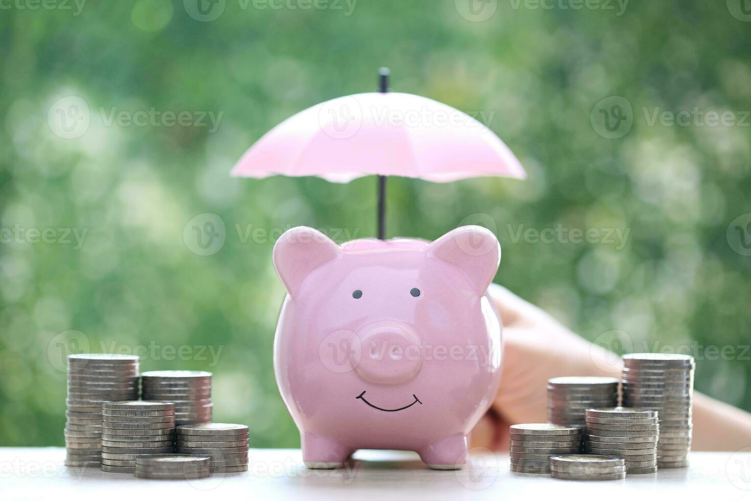 Protection,Piggy bank with hand holding the umbrella on natural green background, Finance insurance and Safe investment concept photo