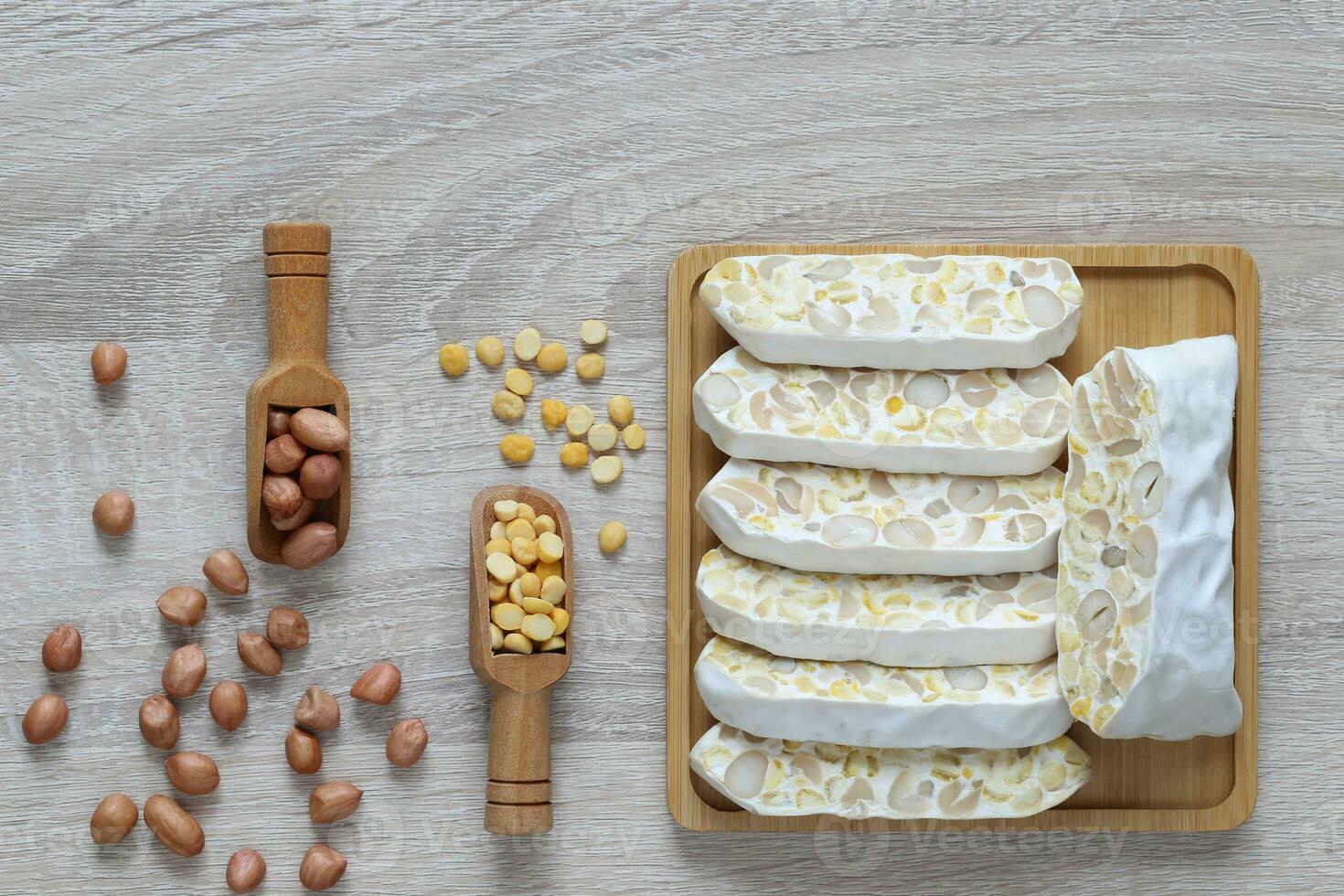 Top view of tempeh slices in a bowl with chick pea and groundnuts on wooder background, Healthy eating concept photo