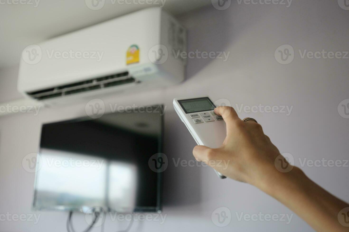 Hand hold remote control directed on the air conditioner photo