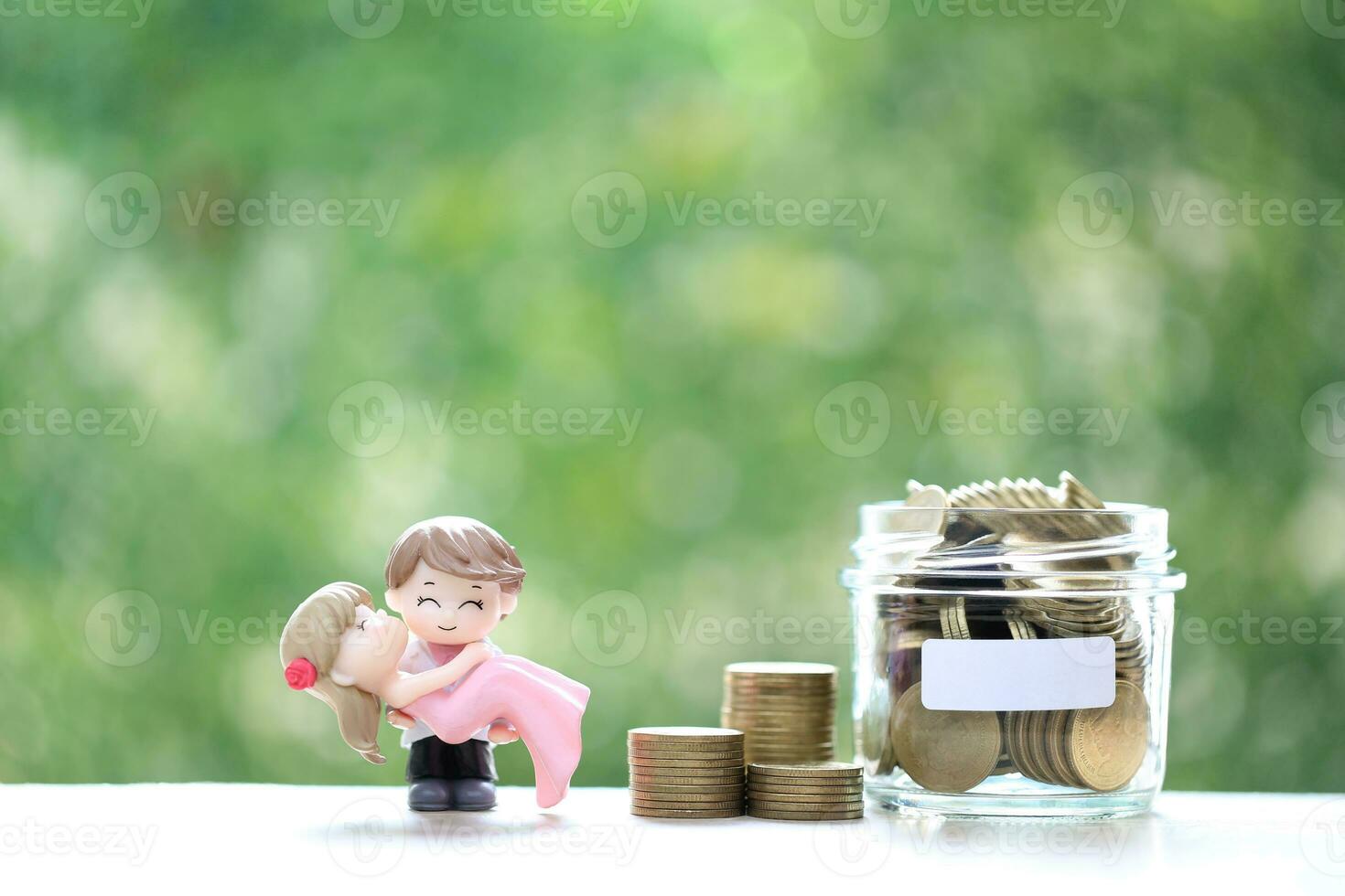 Love couple with coins money in the glass bottle on natural green background, Save money for wedding or family and save money for prepare in future concept photo