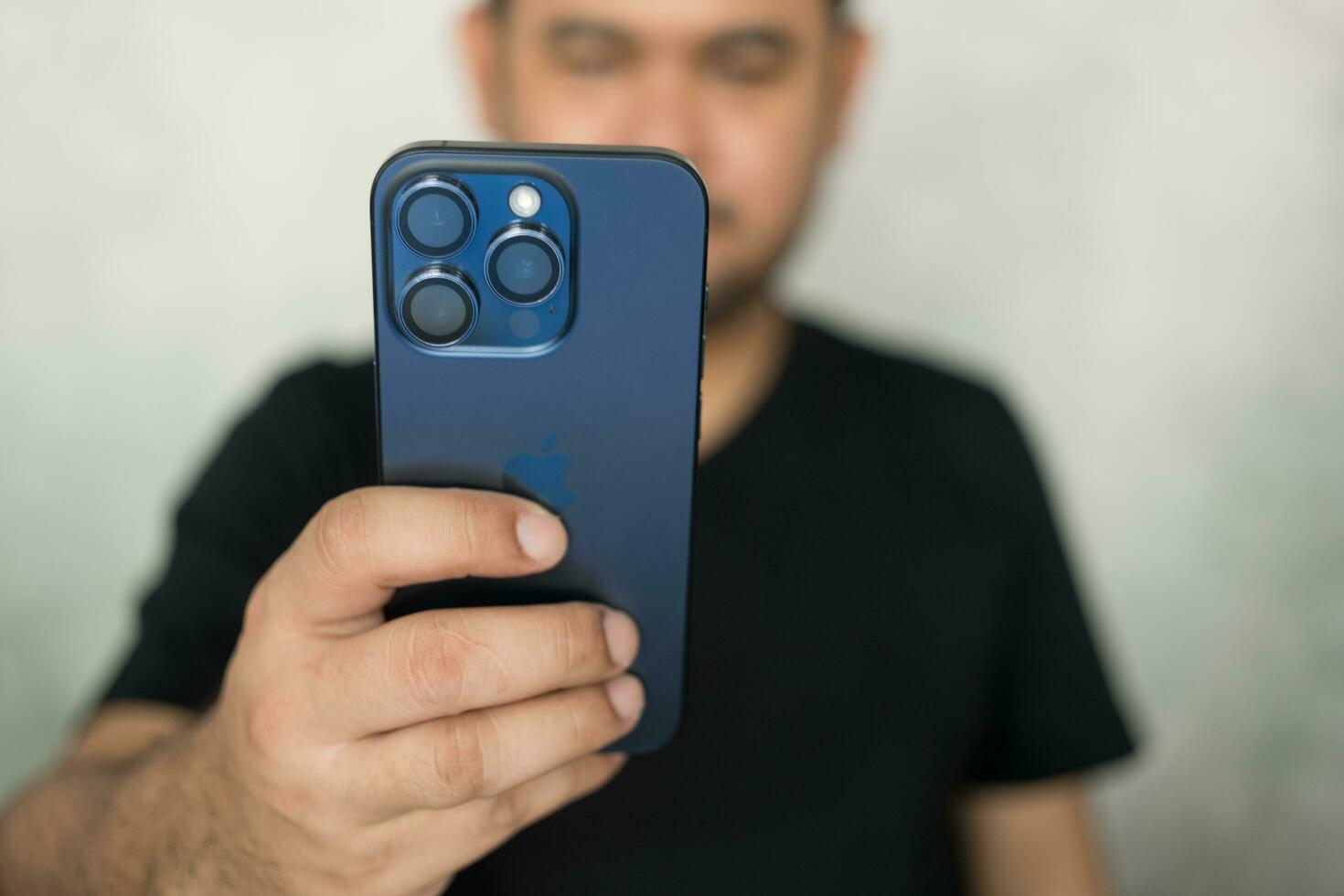 Bangkok, Thailand - December 24, 2023 Man taking selfie photo with a iPhone 15 pro blue titanium.