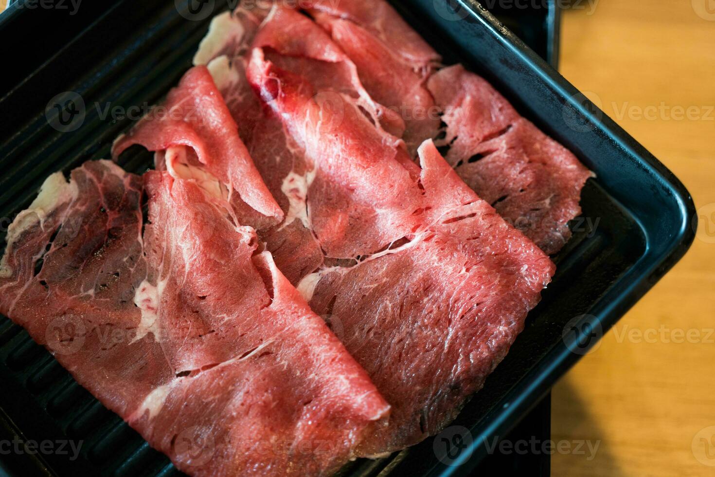 Beef raw slice on black tray for hot pot or sukiyaki photo